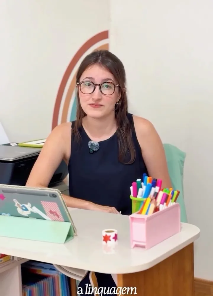 Profissional do Núcleo sentada à mesa de atendimento com canetinhas coloridas e um tablet